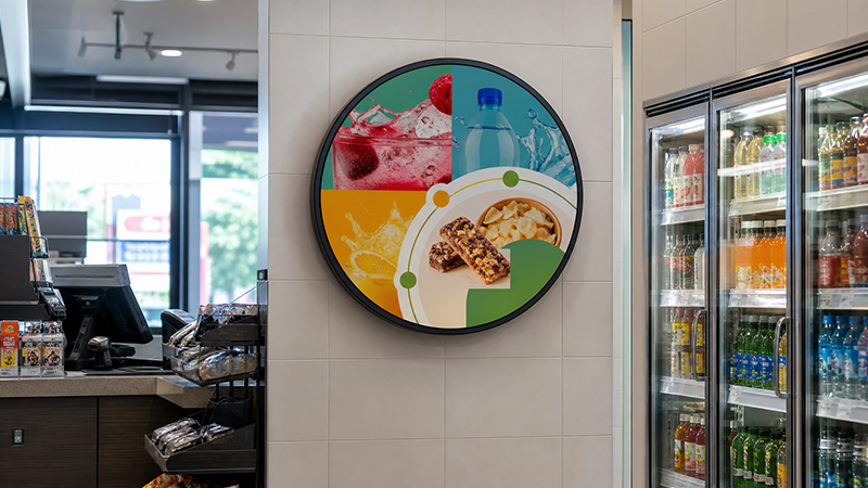 Round LCD display presenting beverage and snack promotions in a convenience store